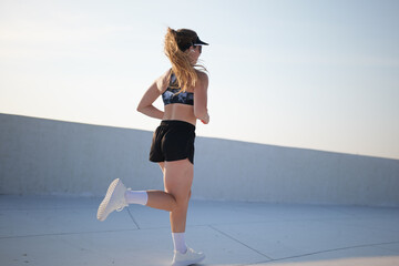 Woman jogging on a rooftop with a city view under a clear sky