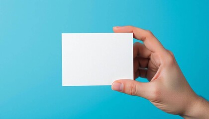 Blank card in hand: A hand holding a clean, blank card against a vibrant, aquamarine backdrop, conveying a message of potential, simplicity, and the promise of personal expression or brand identity.