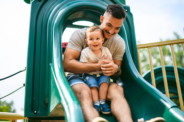 father with child boy is sitting on the slide with it