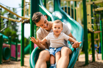father with child boy is sitting on the slide with it