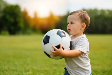 Young Boy on a Green Field in the Park With a Football