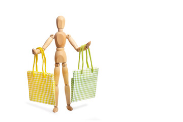 A wooden mannequin toy holding with both hands shopping bags on white background with copy space