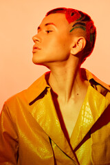 Stylish woman with artistic red shaved hairstyle and yellow textured jacket, posing with a...