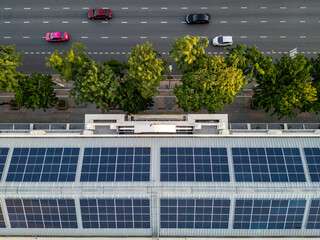 Aerial top view of blue solar photo voltaic panels system on the large industrial factory building roof top or a warehouse. Renewable ecological green energy production concept.