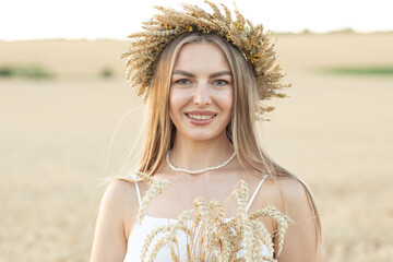 Portrait of a beautiful young woman with wicker basket in wheat field