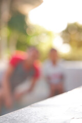 Close up of an empty table for displaying products with a blurred background of people by the pool. Table beside the pool
