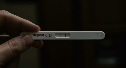 Positive pregnancy test result held in hand expressing hopeful anticipation