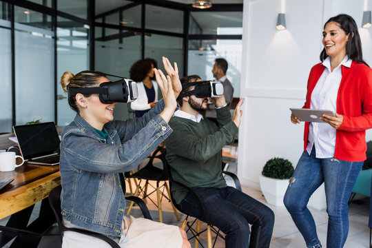 Group of young latin business people using virtual reality glasses during meeting testing VR headset at office in Mexico Latin America. hispanic people at working at job
