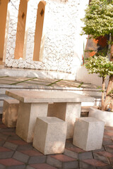 Outdoor cafe or coffee shop with a table and chairs set made of white natural stone. Modern interior design concept and furniture.
