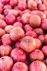 A close-up of a a vibrant red pomegranate from a neatly arranged fruit display at an outdoor farmers market.