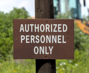 authorized personnel only sign next to construction site with bulldozer vehicle in the background (do not enter work zone forbidden prohibited entry hard hat danger dangerous area) industrial zone