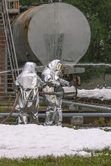 Firefighters in protective clothing use a foam generator to supply foam to extinguish the fire. Foam fire extinguishing technology. The rescue service. Firefighters extinguish the fire.