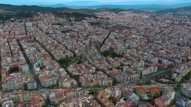 Close aerial of Barcelona : Gaud&iacute;&rsquo;s Sagrada Familia rises inside the perfect Eixample grid, backed by hills - ideal for travel, architecture and urban - planning stories.