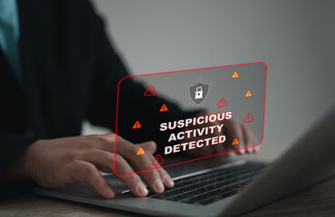 Alert screen shows Suspicious Activity Detected warning on digital security interface while an office worker types on laptop, representing cybersecurity threats, system alerts, and online protection.
