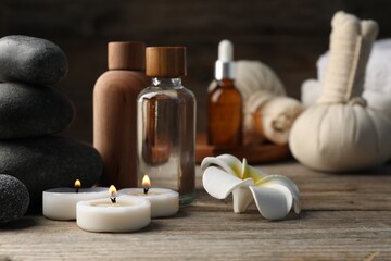 Composition with cosmetic products and spa stones on wooden table, closeup