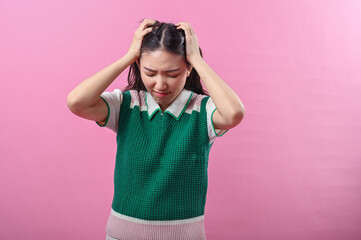 Asian woman pulling her hair in frustration and closing her eyes tightly, expressing extreme stress...