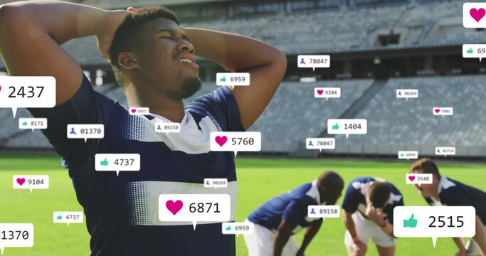 Gripping head soccer player in navy jersey on pitch at stadium, with floating social media icons - Powered by Adobe