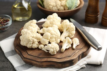 Fresh raw cauliflower florets, spices and knife on grey table, closeup