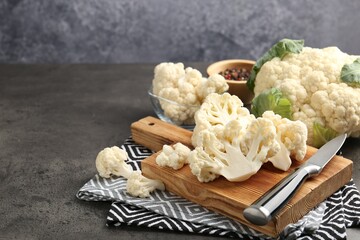 Fresh raw cauliflower florets, spices and knife on grey table, closeup. Space for text