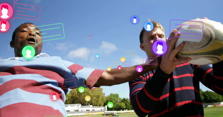 Contesting players in jerseys stretching to secure rugby ball on field, with floating chat icons