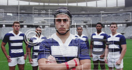 Posing rugby team wearing scrum caps and striped jerseys on stadium pitch with red tape