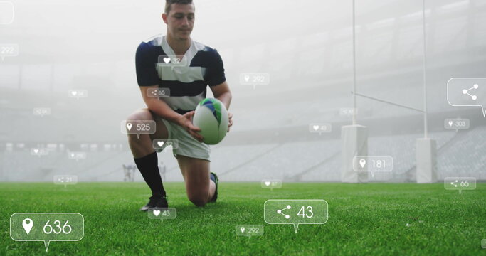 Kneeling rugby player in striped jersey, shorts placing ball on stadium turf, with floating icons - Powered by Adobe