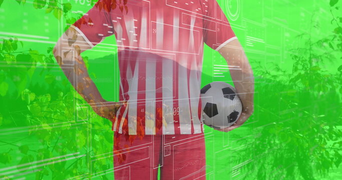 Showing soccer player wearing striped jersey holding ball on green-screen, with digital overlays