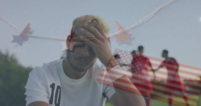 Sitting soccer player in number 10 jersey holding head on park bench, garland, flag overlay - Powered by Adobe