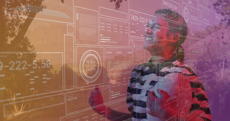 Standing woman wearing VR headset and striped top in park, interacting with HUD data, copy space