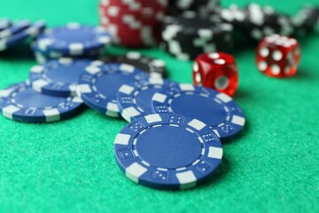 Casino chips and dice on green table, closeup