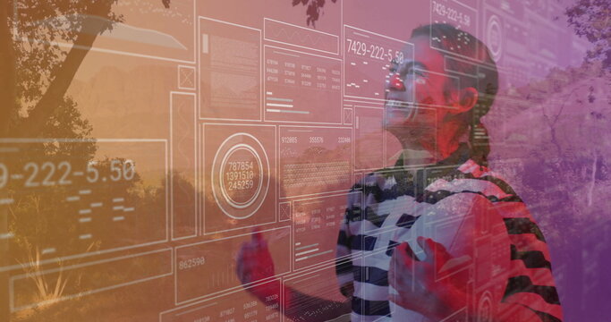 Standing woman wearing VR headset and striped top in park, interacting with HUD data, copy space