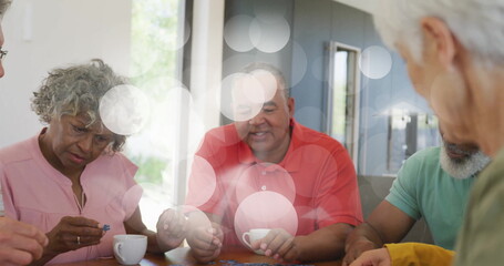 Putting together jigsaw puzzle pieces by four friends in living area, with table mugs eyeglasses