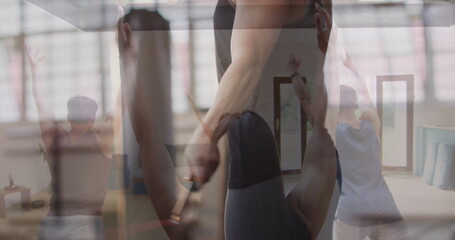 Guiding instructor assisting participant stretching overhead at yoga studio, yoga mats, mirror