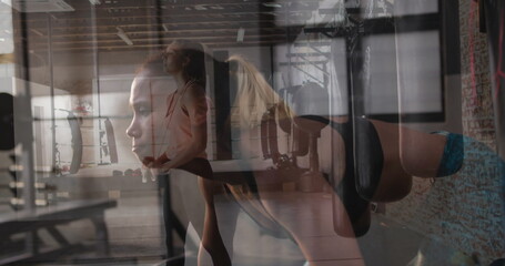 Fitness partners holding squat and performing ring push-ups in fitness studio, with gymnastic rings