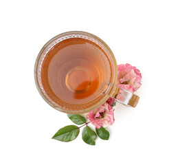 Tasty rose tea in glass cup, flowers and sprig with leaves isolated on white, top view