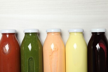 Superfood. Bottles with healthy drinks on light wooden table, flat lay. Space for text