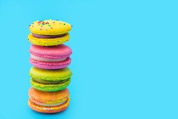 A few brightly colored stacked macarons on blue background. Mixed of colorful macaroni or pasta cake. Tasty and colorful french macarons. Culinary, cooking concept, styling food. Add your text.
