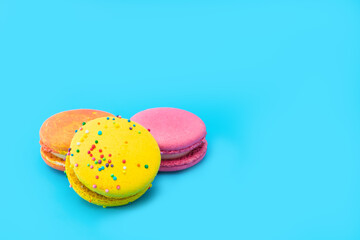 Three brightly colored stacked macarons on blue background. Mixed of colorful macaroni or pasta cake. Tasty and colorful french macarons. Culinary, cooking concept, styling food. Add your text