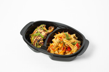 Grilled chicken with green sauce and colorful pasta salad with vegetables on a plate on a white background