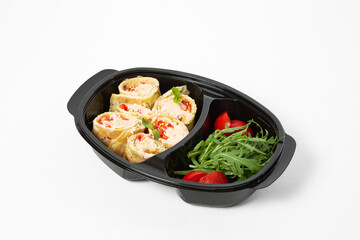 Omelette rolls with vegetables in sauce, served with tomatoes and arugula on a plate on a white background
