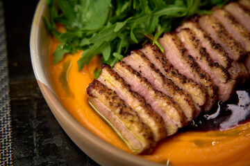 Savory Exquisite Dish Featuring Succulent Slices of Perfectly Cooked Meat Arranged Elegantly Over a Vibrant Sauce and Accompanied by Fresh Green Herbs