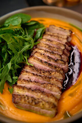 Deliciously Grilled Duck Breast Served on a Bed of Creamy Sweet Potato Puree Accompanied by Fresh Greens for a Taste Sensation