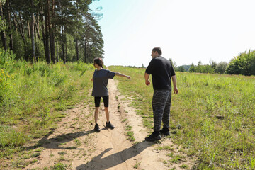 Father and daughter warming up before morning run in a sunlit meadow, performing dynamic stretches and mobility exercises, promoting active lifestyle and family fitness.
