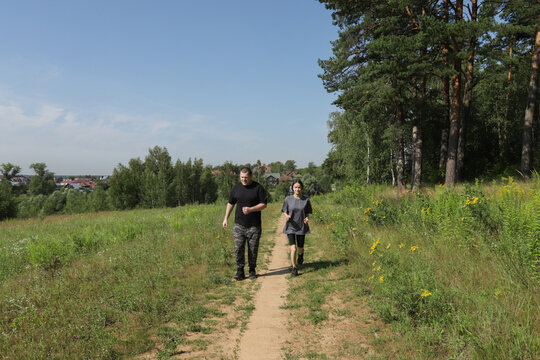 Father and teenage daughter jogging on forest trail, enjoying outdoor exercise together on a sunny morning, promoting healthy family lifestyle and fitness bonding. - Powered by Adobe