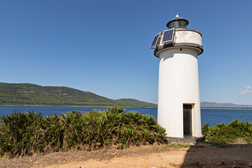 White lighthouse on the sardinian coast in a sunny day. The place is the bay of Porto Conte near the city of Alghero in Sardina, Italy.