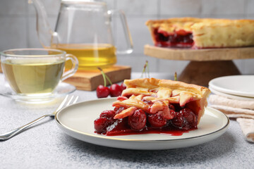 Piece of tasty cherry pie on grey textured table, closeup