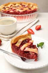 Piece of tasty strawberry pie and berries on white wooden table, closeup