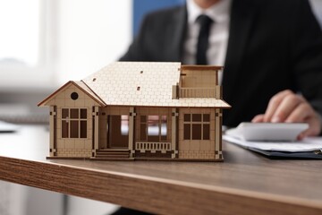 Real estate agent working at desk in office, focus on house model