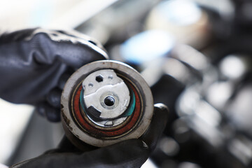 Auto part. Professional mechanic with idler-wheel near open hood of car indoors, closeup. Space for...