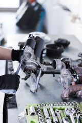 Auto parts. Professional mechanic with starter motor at grey table indoors, closeup